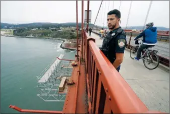  ?? (AP/Eric Risberg) ?? Patrol officer Nicolas Serrano looks out Aug. 3 at a suicide barrier under constructi­on below the Golden Gate Bridge in San Francisco.