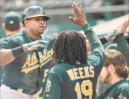  ?? By Kelley L Cox, US Presswire ?? Fitting in: Athletics center fielder Yoenis Cespedes high-fives teammates in the dugout after scoring a run against the Royals in an April 11 game. Cespedes, who left Cuba to sign a four-year, $36 million contract with the A’s, is batting .212 with...