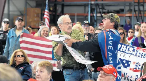  ?? CLOE POISSON/SPECIAL TO THE COURANT ?? A man rips a sign that read,“Trump Lost, Get Over It,”out of the hands of Earl McWilliams at an“America First Rally”in Plainfield, Connecticu­t, on Oct. 23.
