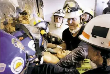  ?? Michael Haritan/PEMA ?? Rescue workers attempt to extract Megan Angelone from an 18-inch hole cut July 12 from a former restaurant next to the collapsed building in Washington, Pa.