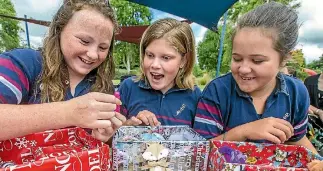  ?? PHOTO: DOUG FIELD/STUFF ?? Pleasant Point primary school students Molly Brady, 13, left, Courtney Gosling,13, and Olivia Otley, 12, have fun packing their shoe boxes for Family Works.