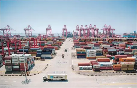  ?? Johannes Eisele AFP/Getty Images ?? A U.S. cargo ship can be seen in the background at the Yangshan Deep-Water Port, an automated cargo wharf in Shanghai, in April.