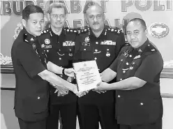  ??  ?? Fazri (right) receives his duties as Kuching district CID chief from Lim (left) while Dev Kumar (second right) and Abang Ahmad look on.