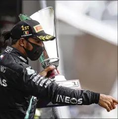  ?? LARS BARON / ASSOCIATED PRESS ?? Mercedes driver Lewis Hamilton of Britain hoists another trophy at the Belgian Grand Prix as he picks up his 89th career victory — only two behind career leader Michael Schumacher — and extends his season lead in the Formula One standings to 47 points.