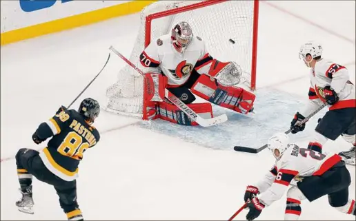  ?? Michael Dwyer / Associated Press ?? Boston's David Pastrnak, left, scores on Ottawa goaltender Kevin Mandolese during the Bruins’ 3-1 win over the Senators on Monday.