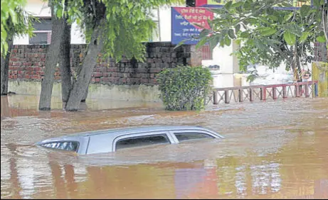  ?? PHOTOS: KESHAV SINGH//HT ?? A car submerged in floodwater at the Baltana police post in Zirakpur on Sunday. The condition at the nearby municipal park was such that swings that stand 10-foot tall were all under water. However, no households were affected in the area.