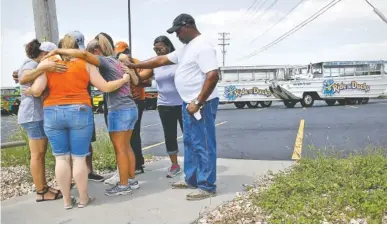  ?? AP PHOTO BY CHARLIE RIEDEL ?? People pray Friday outside Ride the Ducks, an amphibious tour operator involved in a boating accident on Table Rock Lake in Branson, Mo.