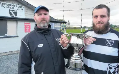  ?? PHOTO: RICHARD DAVISON ?? In memoriam . . . Naylor (left) and son Aydan Edwards hold the Caelib Edwards Memorial Trophy at the Crescent Rugby Club, in Kaitangata, yesterday. North vs South select teams from South Otago will vie for the newlynamed trophy for the first time in...