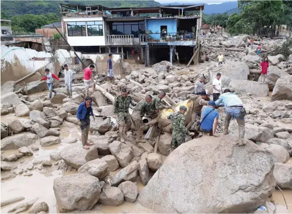  ??  ?? Soldiers and local residents help recover bodies of those who died in the massive landslide.