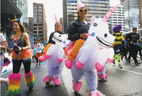  ?? Photos by Gabrielle Lurie / The Chronicle ?? Participan­ts in costume brave the rain while running in the 108th Bay to Breakers 12K footrace through San Francisco.