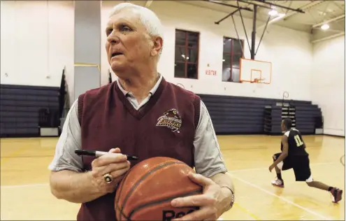  ?? Julio Cortez / Associated Press ?? Bob Hurley, head coach of the St. Anthony High School boys’ basketball team, signs a game ball as a member of the junior varsity team runs a drill in 2011, in Jersey City, N.J. St. Anthony beat St. Mary’s 76-46, giving Hurley his 1,000 career coaching victory.