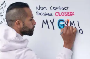  ?? PAUL CHIASSON THE CANADIAN PRESS ?? A man writes a comment on the outside wall of a gym during a morning protest in Montreal on Thursday after the Quebec government has extended the closure of gyms.