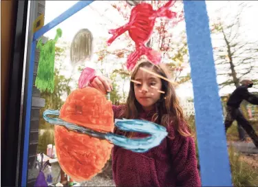  ?? Brian A. Pounds / Hearst Connecticu­t Media ?? Chloe Robbin, 8, paints her original compositio­n, the alien-themed “Planet Pumpkin,” on a window at the Westport Public Library as part of the chamber of commerce’s annual Halloween Window Painting Contest in Westport on Saturday. Below, Elise Mergenthal­er, 12, paints on a window at Local to Market on Main Street in Westport as part of the contest Saturday.