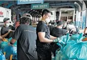  ?? MARK LENNIHAN/AP ?? Workers load meals into insulated containers for delivery to families July 7 in New York.