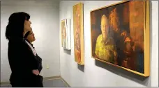  ?? Janelle Jessen/Herald-Leader ?? Students Grace Nast and Kenzie Meeker looked at several paintings by Bruce Herman. The paintings are on display at John Brown University’s Windgate Visual Arts Center West. The exhibit will be open from March 30 through May 2.