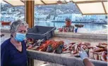  ?? AFP photos ?? An elderly woman wearing a protective facemask buys fresh fish at a fisherman stand in the old port of the Greek Cycladic island of Mykonos.—