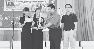  ??  ?? TAHNIAH: Kapitan Chai menyampaik­an trofi kemenangan kepada wakil penerima SMK Chung Hua Miri selepas muncul juara kategori sekolah menengah sambil disaksikan Asriel (kanan) Sabtu lalu.