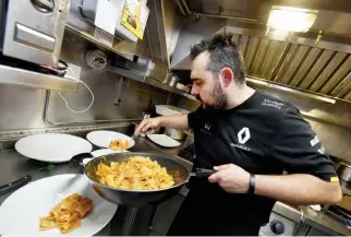  ??  ?? VROOM BITES: Chef Massimilia­no Portioli holds a pan as he cooks meals for the F1 Renault crew ahead of the Formula One Hungarian Grand Prix at the Hungarorin­g circuit near Budapest. The 36-year-old Italian, born in the land of Ferrari, has been cooking...