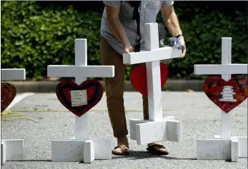  ?? PATRICK SEMANSKY — THE ASSOCIATED PRESS FILE ?? In this file photo, a volunteer prepares to place crosses for victims of a mass shooting at a municipal building in Virginia Beach, Va., at a nearby makeshift memorial. The U.S. has recorded nearly 20 mass killings so far this year, including the one in Virginia Beach, the majority of them domestic violence massacres that receive scant national attention compared to high-profile public shootings at schools, churches and concerts in recent years.