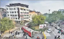  ?? BIPLOV BHUYAN/HT PHOTO ?? Locals and police personnel take a look at the gutted rooftop of Hotel Arpit Palace in Karol Bagh on Tuesday. The blaze is suspected to have been caused by a short-circuit in the air-conditione­r in one of the rooms.
