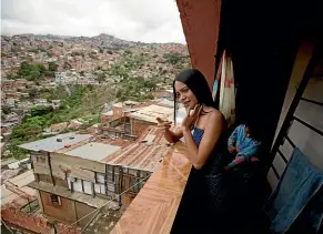  ?? AP ?? Johandrys Colls, left, speaks with her sister Camila on the balcony of their home, in a slum on the outskirts of Caracas, Venezuela.