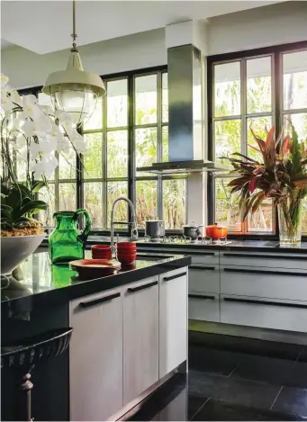  ??  ?? The garden kitchen is flooded with natural light from all sides, with an imposing 1950s Thai teak cabinet taking pride of place