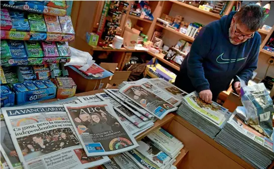  ?? AP ?? A shopkeeper in Pamplona, northern Spain counts coins next to Spanish newspapers featuring the results of the Catalan regional election. The vote failed to clarify the restive region’s immediate future.