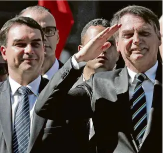  ?? Ricardo Moraes - 6.mai.19/Reuters ?? O presidente Bolsonaro com o filho Flávio em cerimônia na Academia Militar do Rio