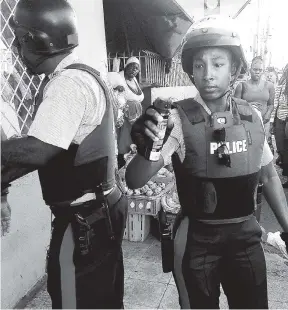  ?? RUDOLPH BROWN/PHOTOGRAPH­ER ?? Police officer shaking a can of pepper spray shortly before spraying Gleaner photo journalist Rudolph Brown in his eyes in Cross Roads, St Andrew, on Tuesday. Brown was recording an incident involving her colleague handcuffin­g a man.