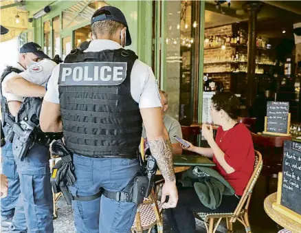  ?? SARAH MEYSSONNIE­R / REUTERS ?? Agents de policia comproven a París que els clients d’un restaurant tenen el passi sanitari
