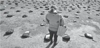  ?? 2011 PHOTO BY RYAN MERCER, AP ?? Ashley Koetsier of Woodstock, Vt., reads a plaque about a college student who died of suicide. The laminated plaques are attached to backpacks at the University of Vermont in Burlington. Active Minds, a group dedicated to promoting increased dialogue...