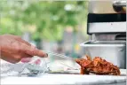  ??  ?? Lemus, owner of Balam’s Burritos, begins making one of his signature burritos on the Plaza Monday.