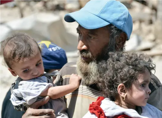  ?? PHOTO AFP ?? Cet homme, qui était pris au piège par les djihadiste­s de l’état islamique, a enfin pu s’échapper avec ses enfants lorsque les forces irakiennes ont libéré une partie du Vieux Mossoul. Selon L’ONU, des milliers de civils sont retenus comme boucliers...