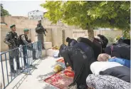  ?? Oded Balilty / Associated Press ?? Palestinia­n women heed an appeal from clerics to pray in the streets in protest of security measures.