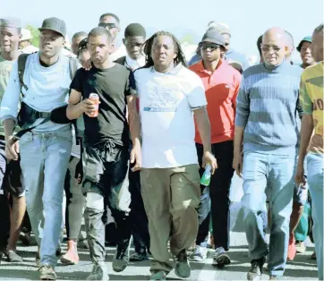  ?? Picture: LETLHOGONO­LO MATLAOPANE ?? HEROES: Thato Molosankwe (brown pants) and Jesse Le Roux, in black, were flanked by well wishers as they entered Mahikeng after spending a month on the road walking from Cape Town to raise awareness of the abuse of women and children.