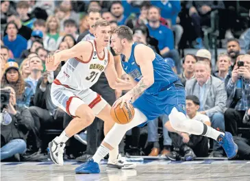  ?? ?? NEW MILESTONE: The Mavericks’ Luka Doncic, right, is defended by the Nuggets’ Vlatko Cancar during their game in Dallas.