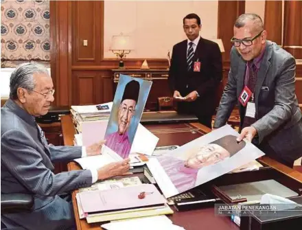  ?? PIC COURTESY OF INFORMATIO­N DEPARTMENT ?? Informatio­n Department visual communicat­ions and graphics division director Mohd Roffee Mohamad presenting portraits for Prime Minister Tun Dr Mahathir Mohamad to choose in Putrajaya yesterday.