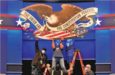  ?? PATRICK SEMANSKY/ASSOCIATED PRESS ?? Workers adjust a sign Monday in preparatio­n for the first presidenti­al debate in Cleveland.