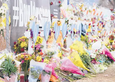  ?? DAVID ZALUBOWSKI/AP ?? Bouquets are stacked in front of crosses outside the King Soopers grocery store in Boulder, Colorado.