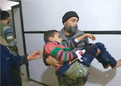  ?? Reuters ?? A man takes a wounded child to hospital after heavy shelling in the rebel-held besieged town of Douma, eastern Ghouta in Damascus on Sunday. —