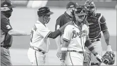  ?? MICHAEL WYKE/AP ?? Braves third base coach RonWashing­ton walks with Ronald Acuna Jr., center, during the third inning in Game 1 of the NLDS against the Marlins on Tuesday.