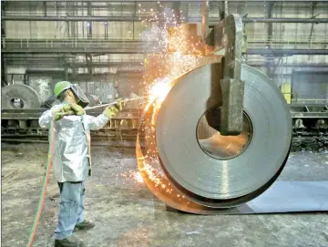  ?? — Reuters photo ?? A worker cuts a piece from a steel coil at the Novolipets­k Steel PAO steel mill in Farrell, Pennsylvan­ia, US.