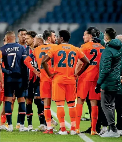  ?? AP ?? Paris SaintGerma­in and Basaksehir players gather on the pitch after an alleged racial slur from the fourth official towards Basaksehir assistant coach Pierre Webo. They would soon walk off with both clubs posting messages in support of Webo. The match was postponed until today.