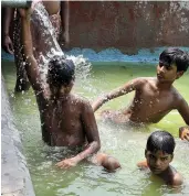  ?? — BUNNY SMITH ?? Children spend time in a water tank to beat the heat in New Delhi on Friday.