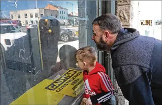  ?? BILL LACKEY/STAFF ?? Trent Spriggs and his son, Tyrion, peek through one of the windows of the Douglas Hotel as they check out the renovation­s going on inside Friday.