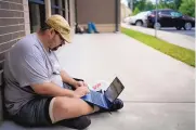 ?? BRYAN WOOLSTON/ASSOCIATED PRESS ?? Barlow Mitchell sits on the ground outside the Lee County Public Library while he uses the public WiFi in Beattyvill­e, Ky., in late July.