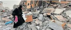  ?? | Reuters ?? A PALESTINIA­N woman searches for her belongings after her apartment was destroyed in an Israeli raid in Nuseirat, in the central Gaza Strip yesterday.