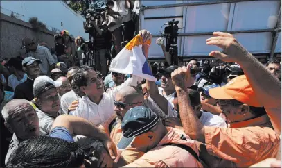  ?? Fernando Llano The Associated Press ?? National Assembly President Juan Guaido, top left, is surrounded Sunday by bodyguards as he leaves an opposition rally in Caraballed­a, Venezuela. The U.S. has backed the idea of him assuming the presidency to end the country’s deepening crisis.