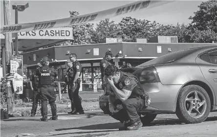  ?? MATT STONE/ USA TODAY NETWORK ?? Louisville police were on guard inside police tape at the intersecti­on of 26th and Broadway on Monday after a man was shot and killed by police and National Guard personnel outside Dino’s Market.