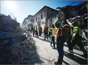  ?? FILIPPO MONTEFORTE/AFP ?? Rescuers walk next to ruins in the destroyed central street of Amatrice in central Italy yesterday after a strong earthquake struck on Wednesday, killing at least 247 people.